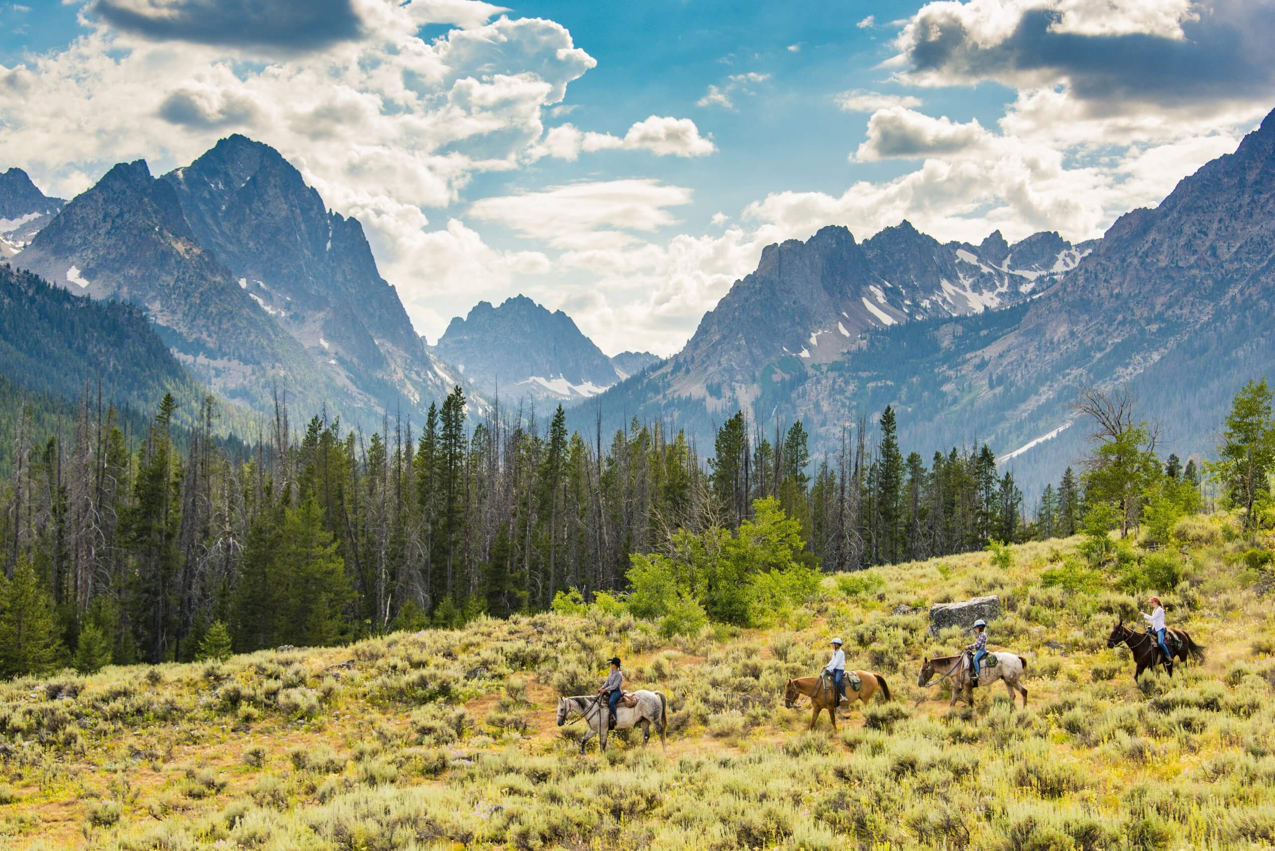 People horseback riding in the Sawtooth Mountains.