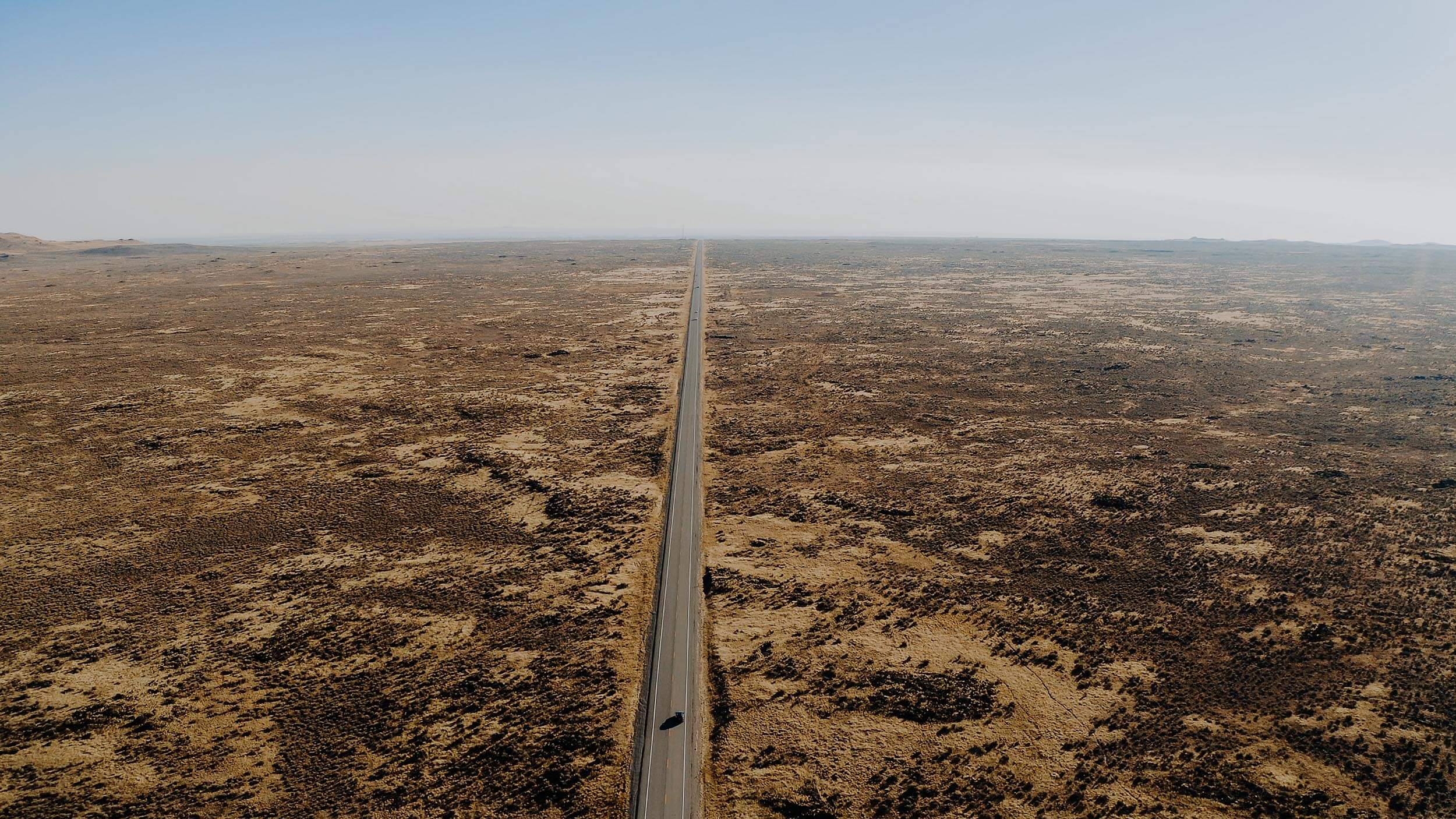 overhead view of a straight highway crossing through a desert landscape