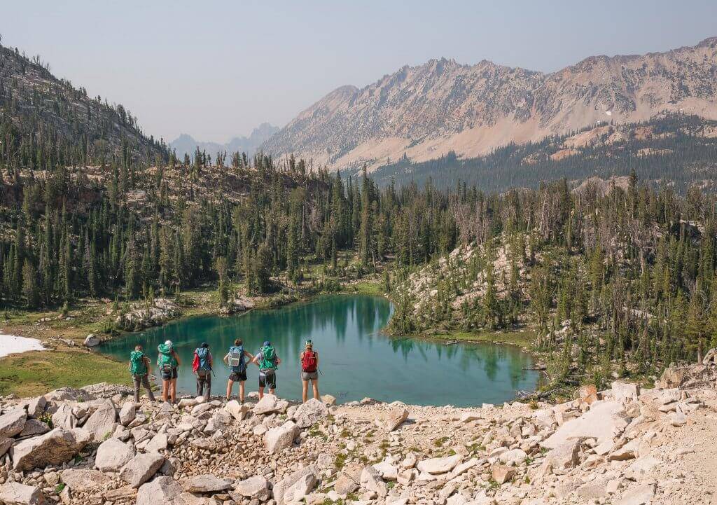 people standing on mountain looking at a lake