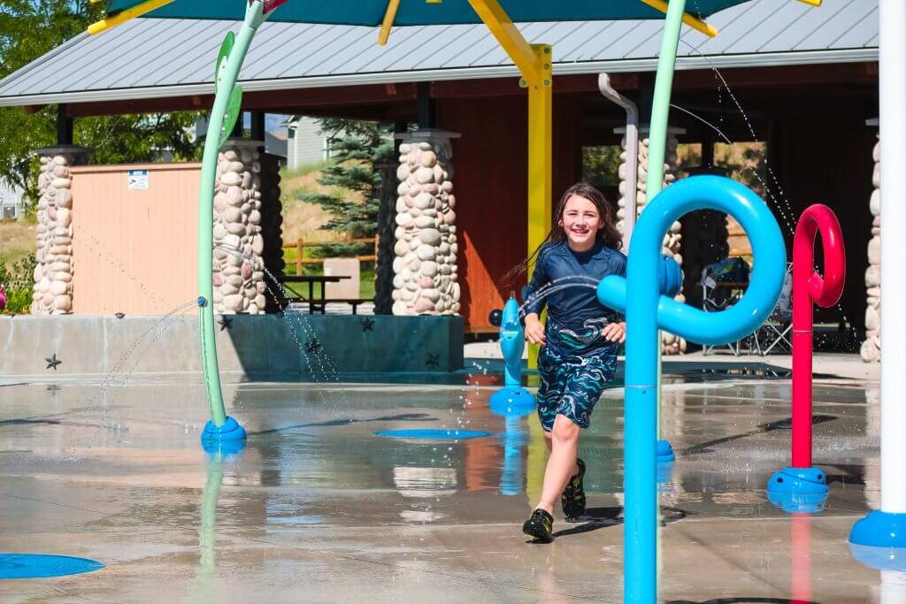 young boy running through the water of a splash pad