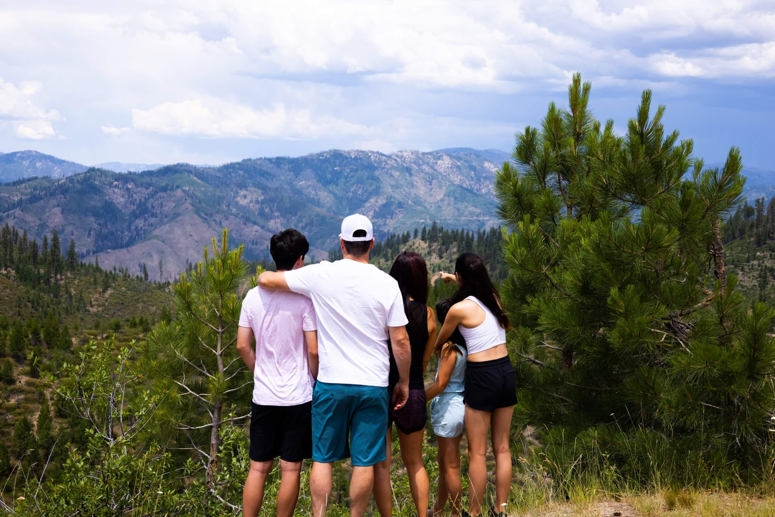 a family on a trail overlooking the Sawtooth Mountains and a forest of trees