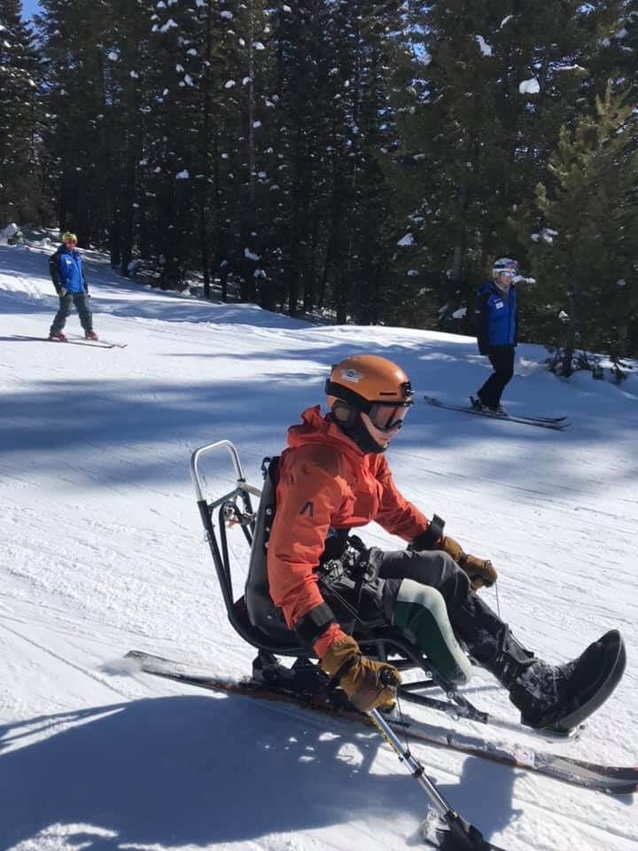 skier in sit ski going down snowy ski slope