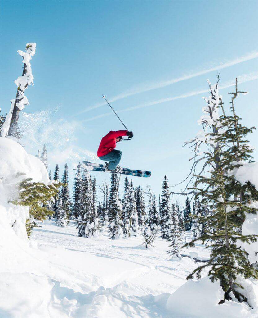 A person on skis in a red jacket makes a jump at Brundage Mountain Resort.