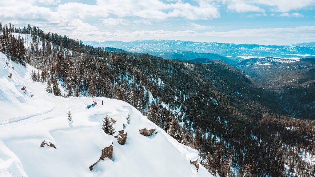 An aerial shot of a group touring Brundage Mountain on snowmobile during the winter. 