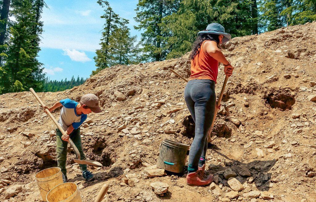 A woman and child digging in a pile of dirt of star garnet. 