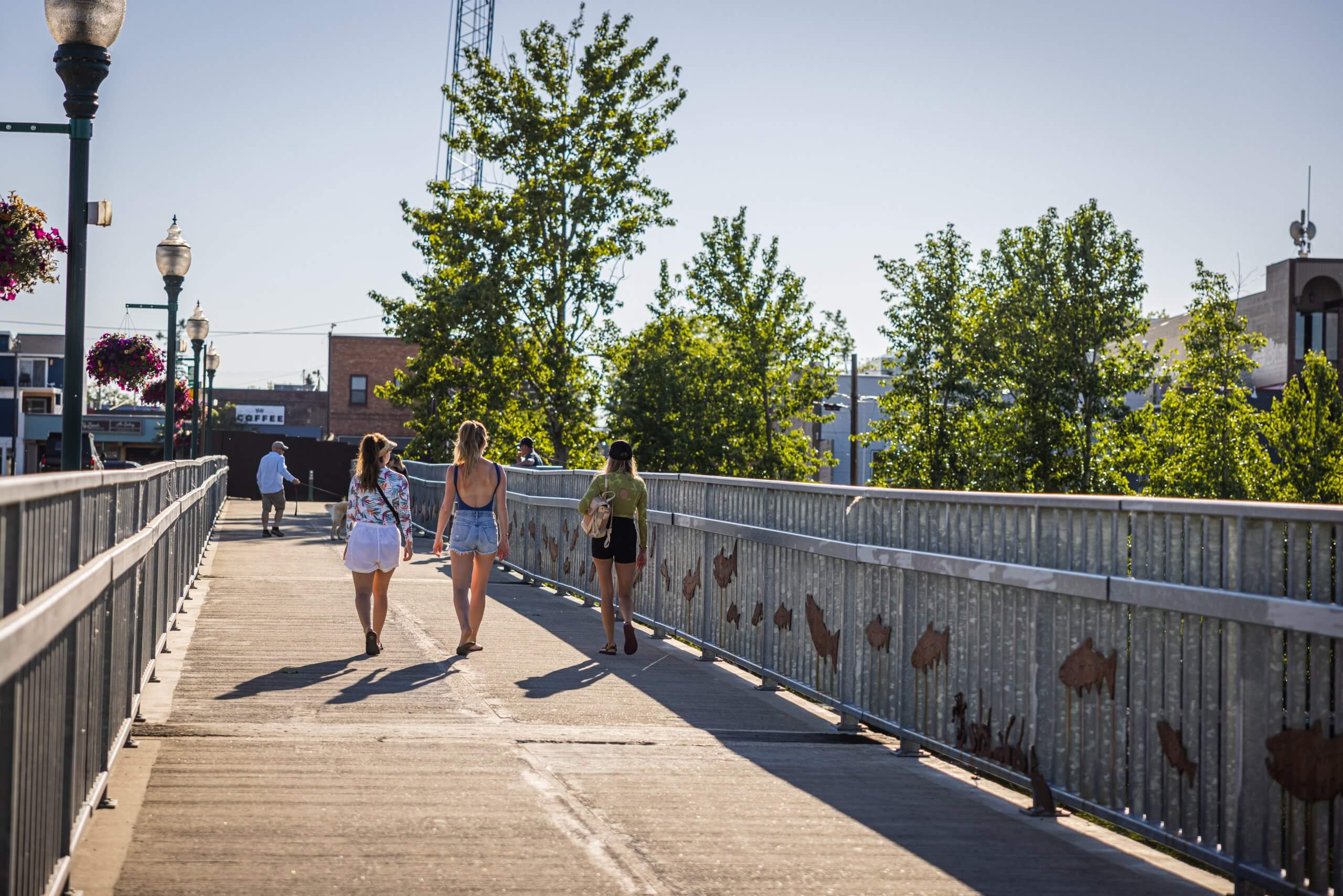 A group of three people walk across a bridge in downtown Sandpoint.