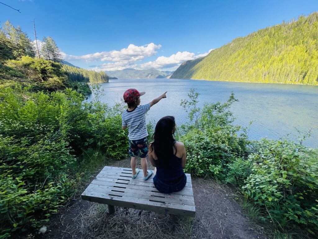 a mother and son sit on a bench overlooking the scenic Lake Pend Oreille at Farragut State Park.