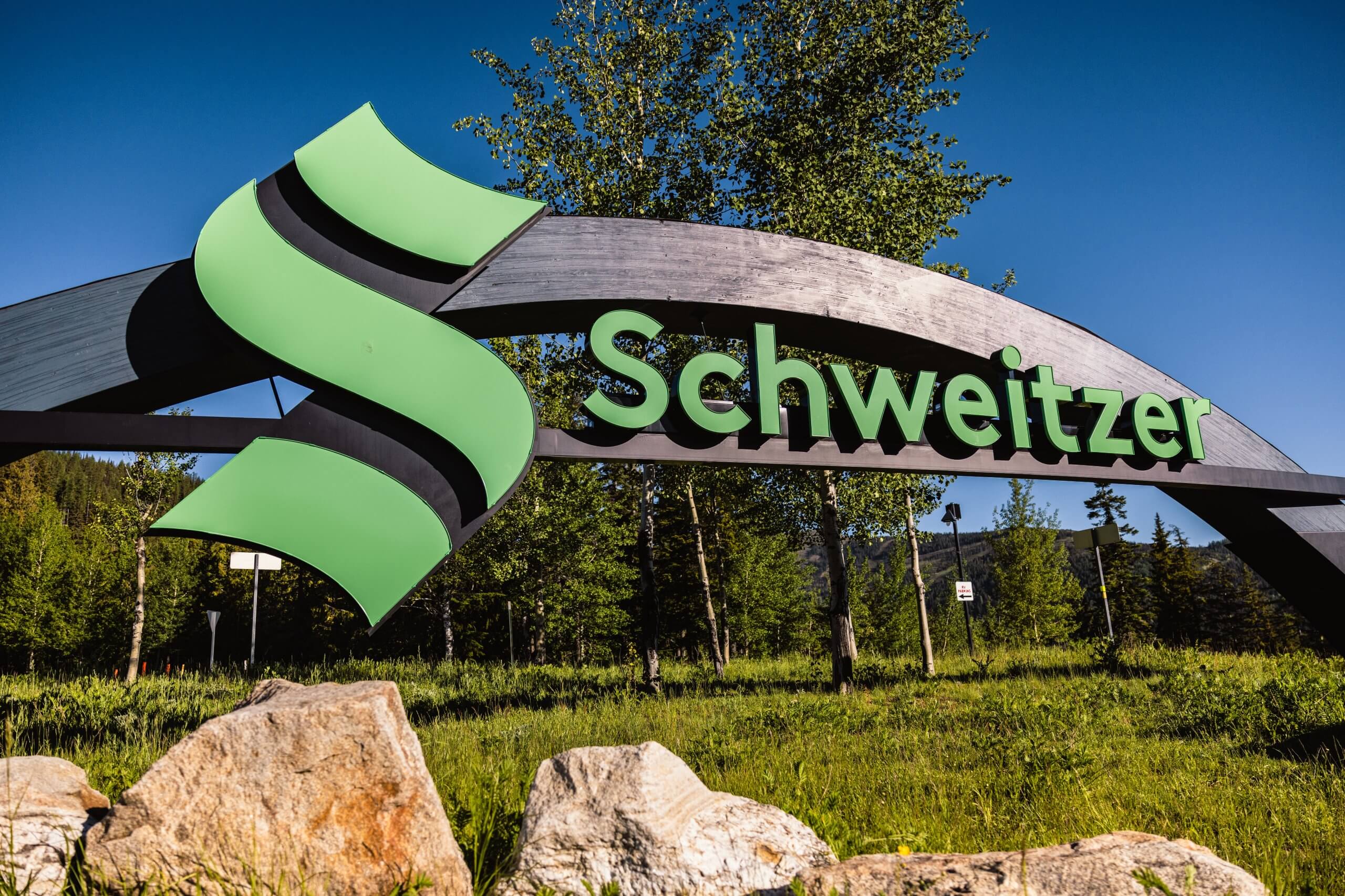 A green and metal sign for Schweitzer.