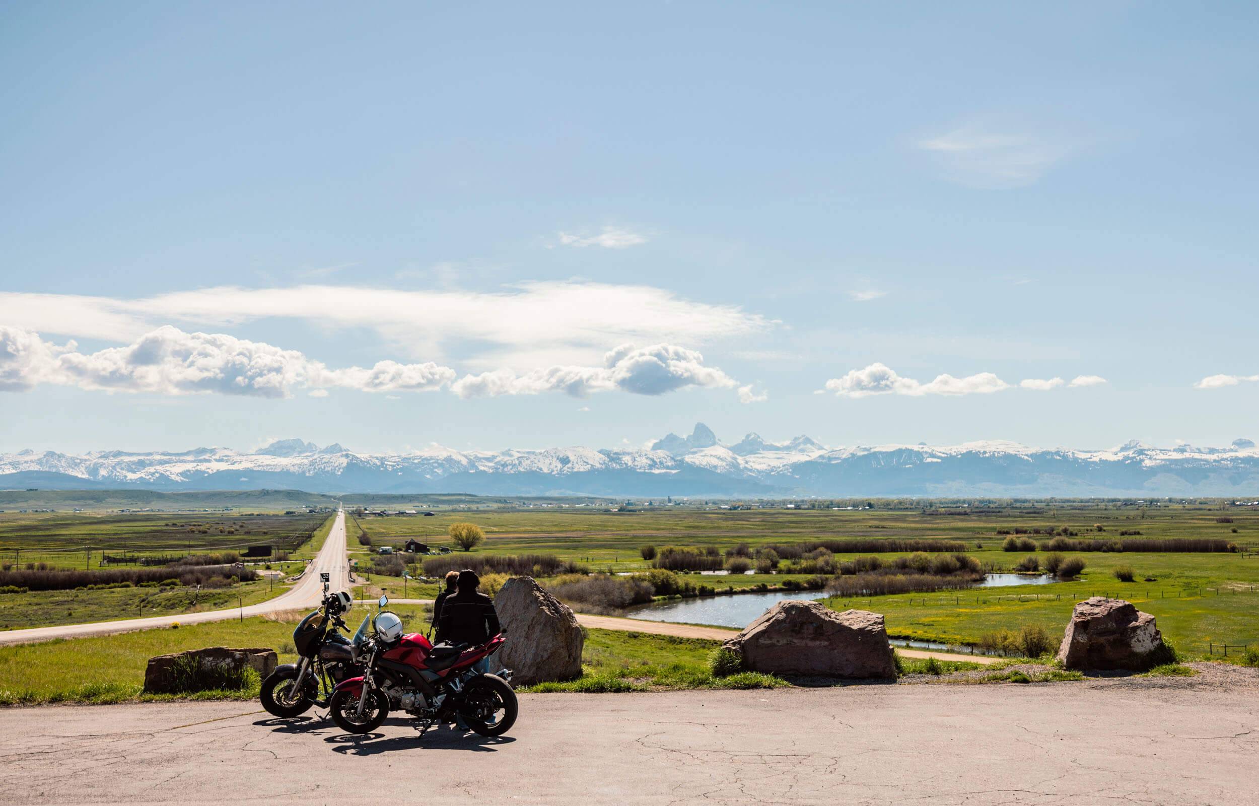 Two people overlooking the Teton Mountains on their motorcycles.