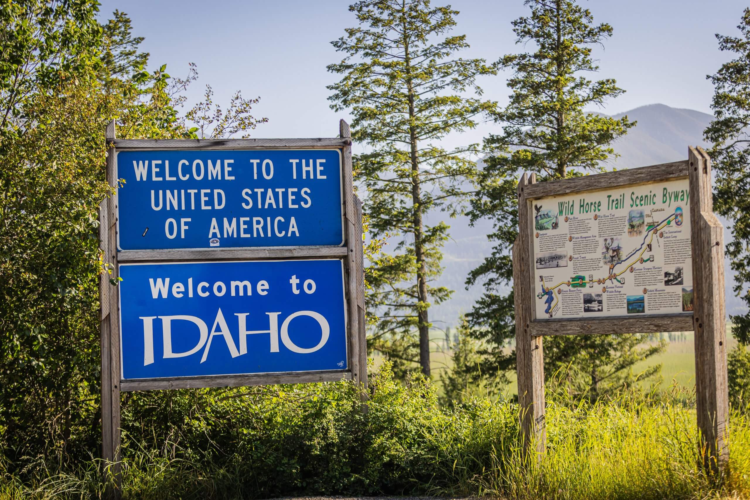 Signage welcoming visitors to the United States and Idaho besides an informational sign about the Wild Horse Trail Scenic Byway.