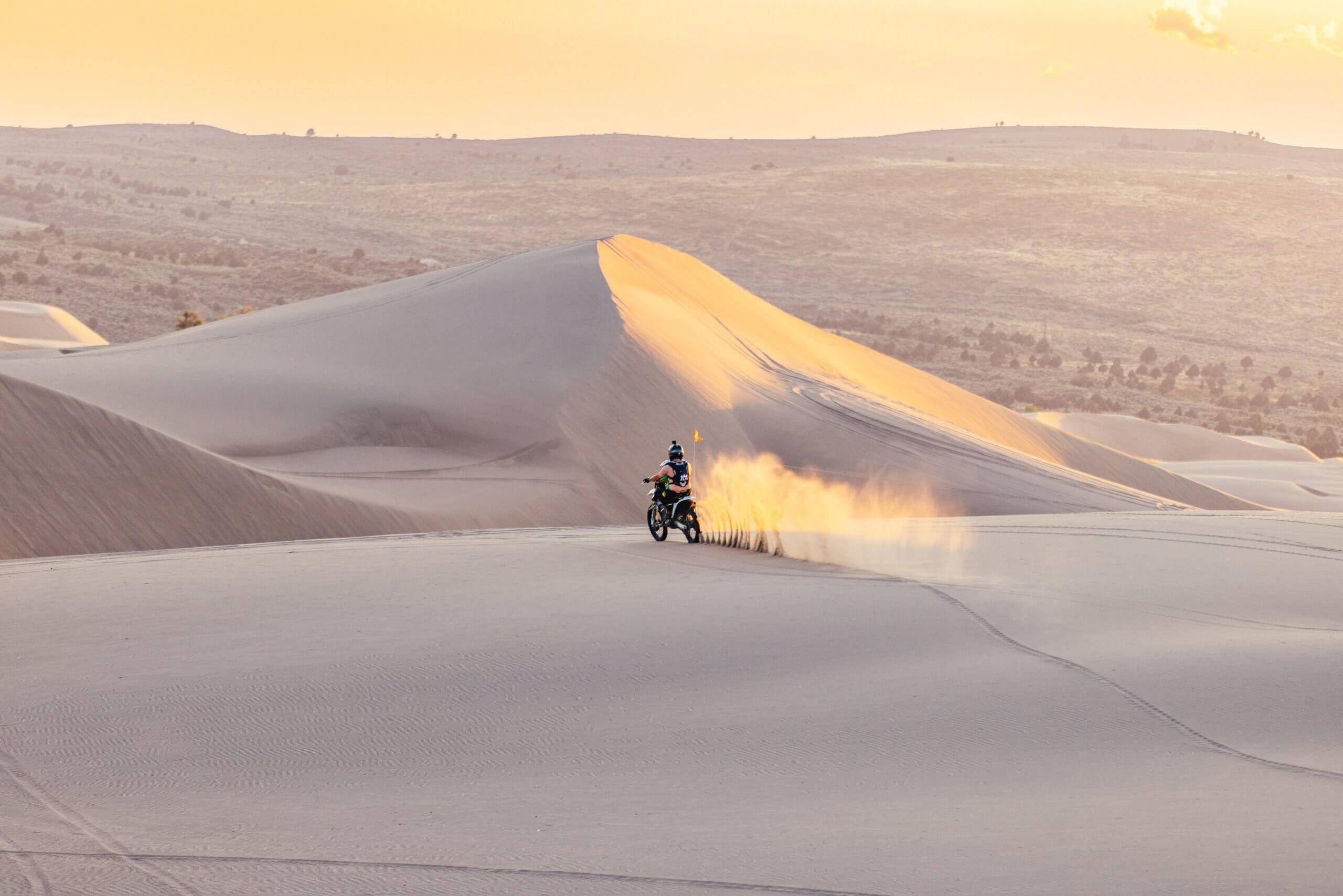 a person riding a dirt bike through the sand at saint anthony sand dunes
