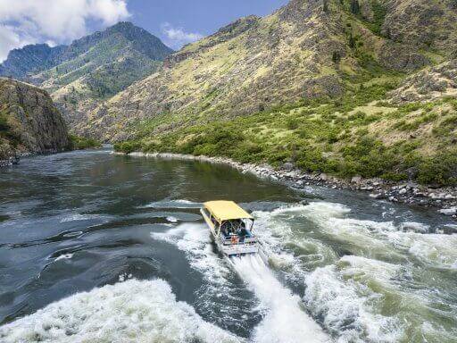 A yellow jet boat traverses the Snake River in Hells Canyon.