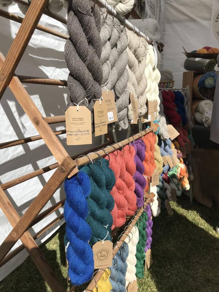 colored bundles of hand-spun wool hang from a wooden rack