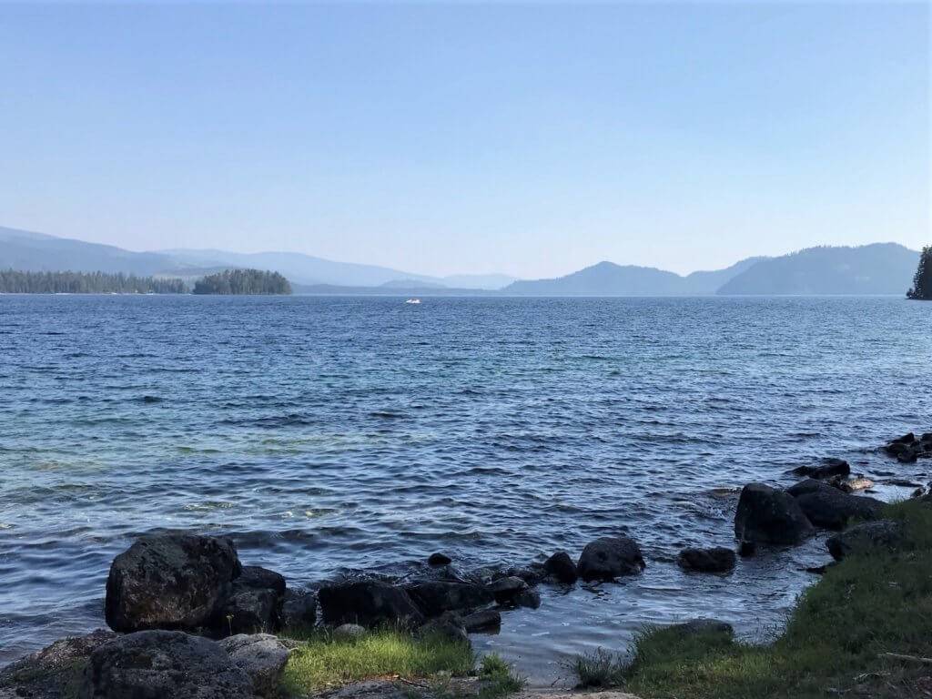 looking at a lake from shore with rocky edges and mountains off in distance