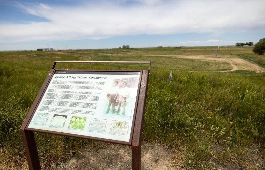 An interpretive trail sign before a sprawling field at Minidoka National Historic Site.