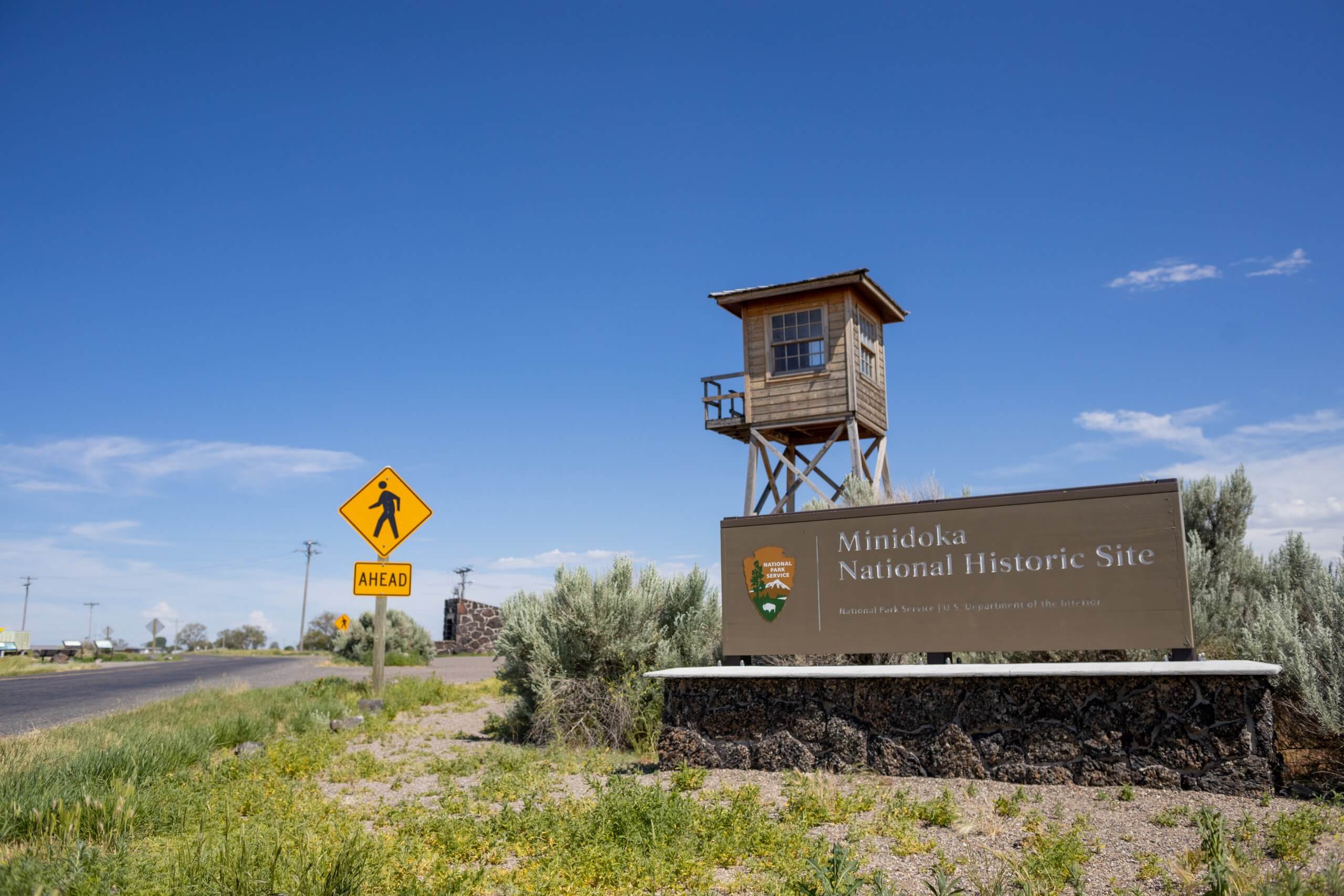 Signage marking the entrance of Minidoka National Historic Site, in front of a historic watchtower.
