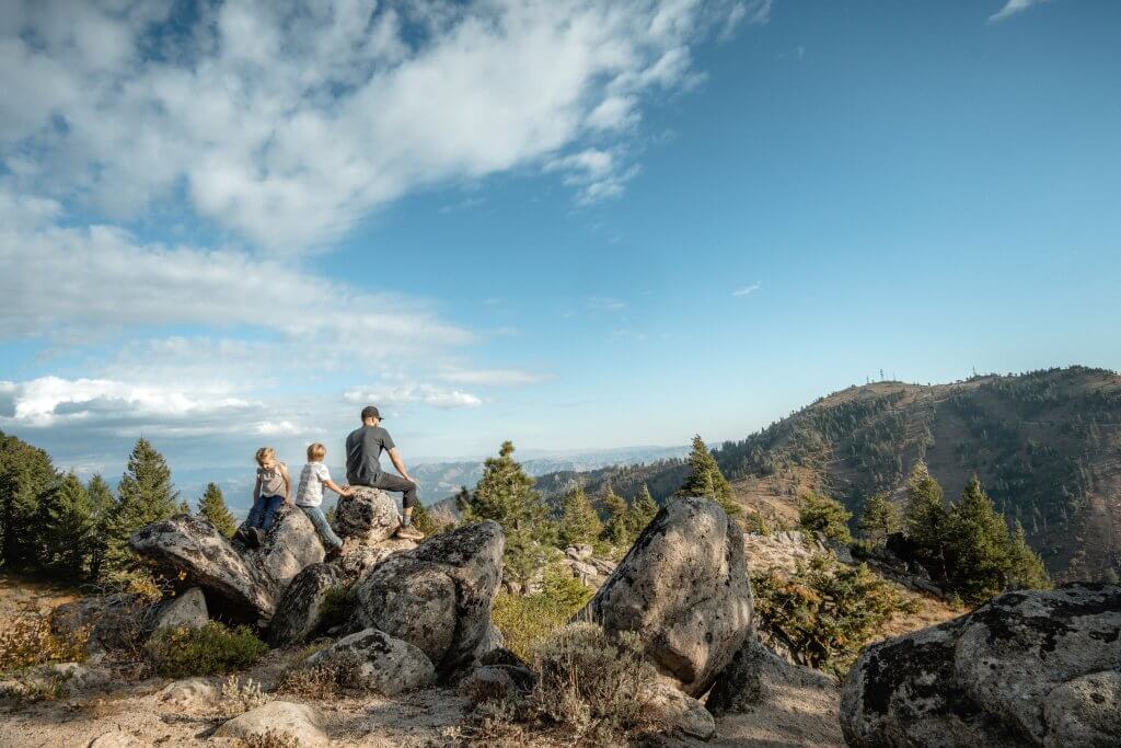 A family sits on a variety of boulders overlooking the valley at Mores Mountain.