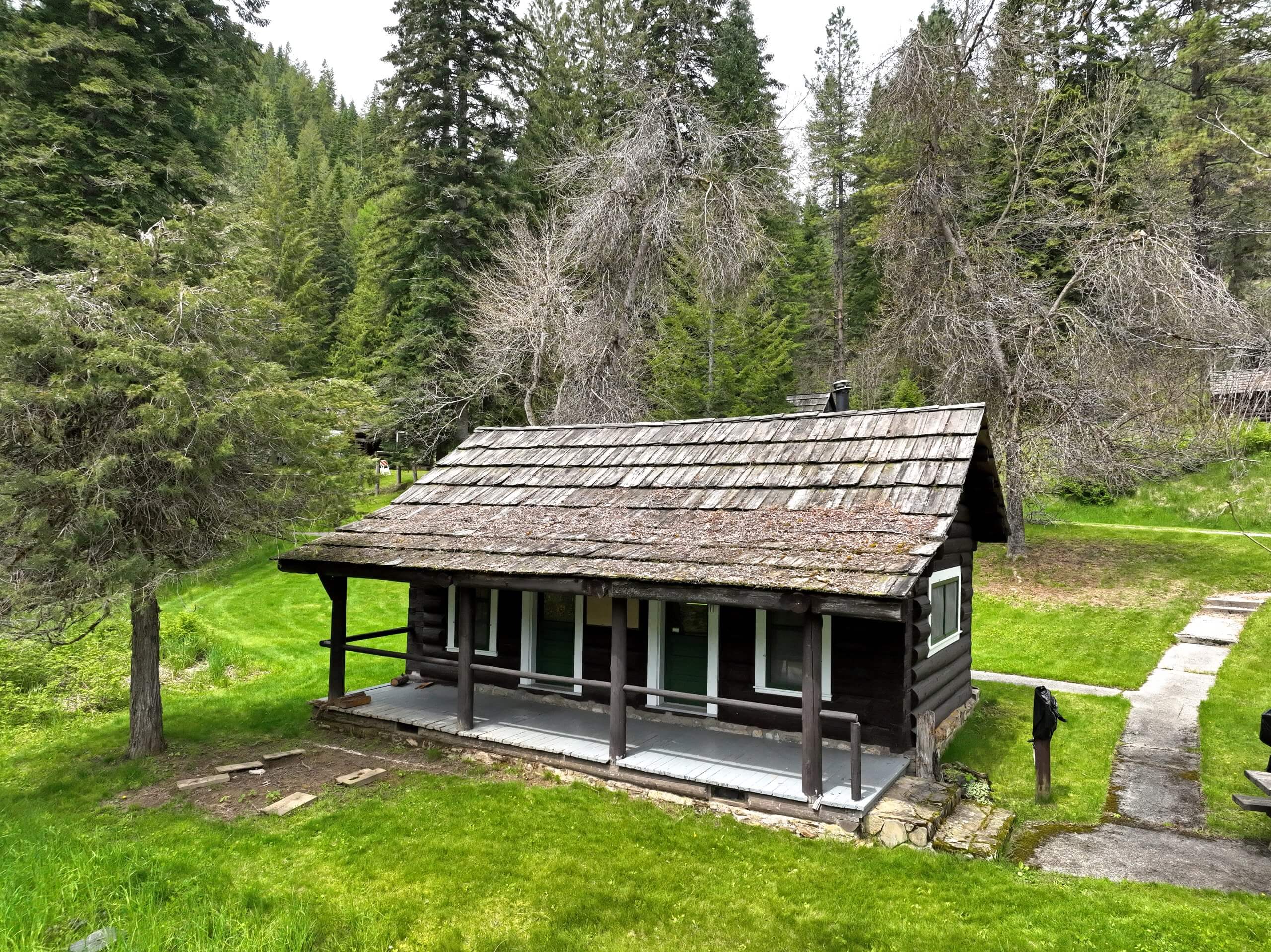 Log cabin surrounded by trees and grass.