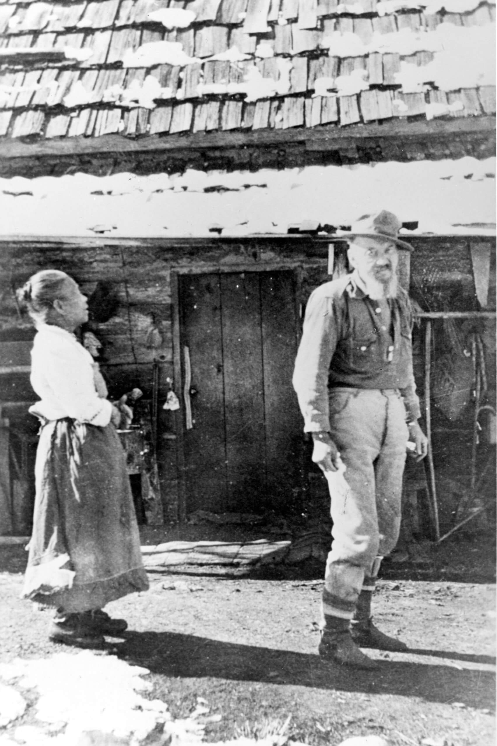 A black-and-white photo of Polly and Charlie Bemis standing in front of their cabin.