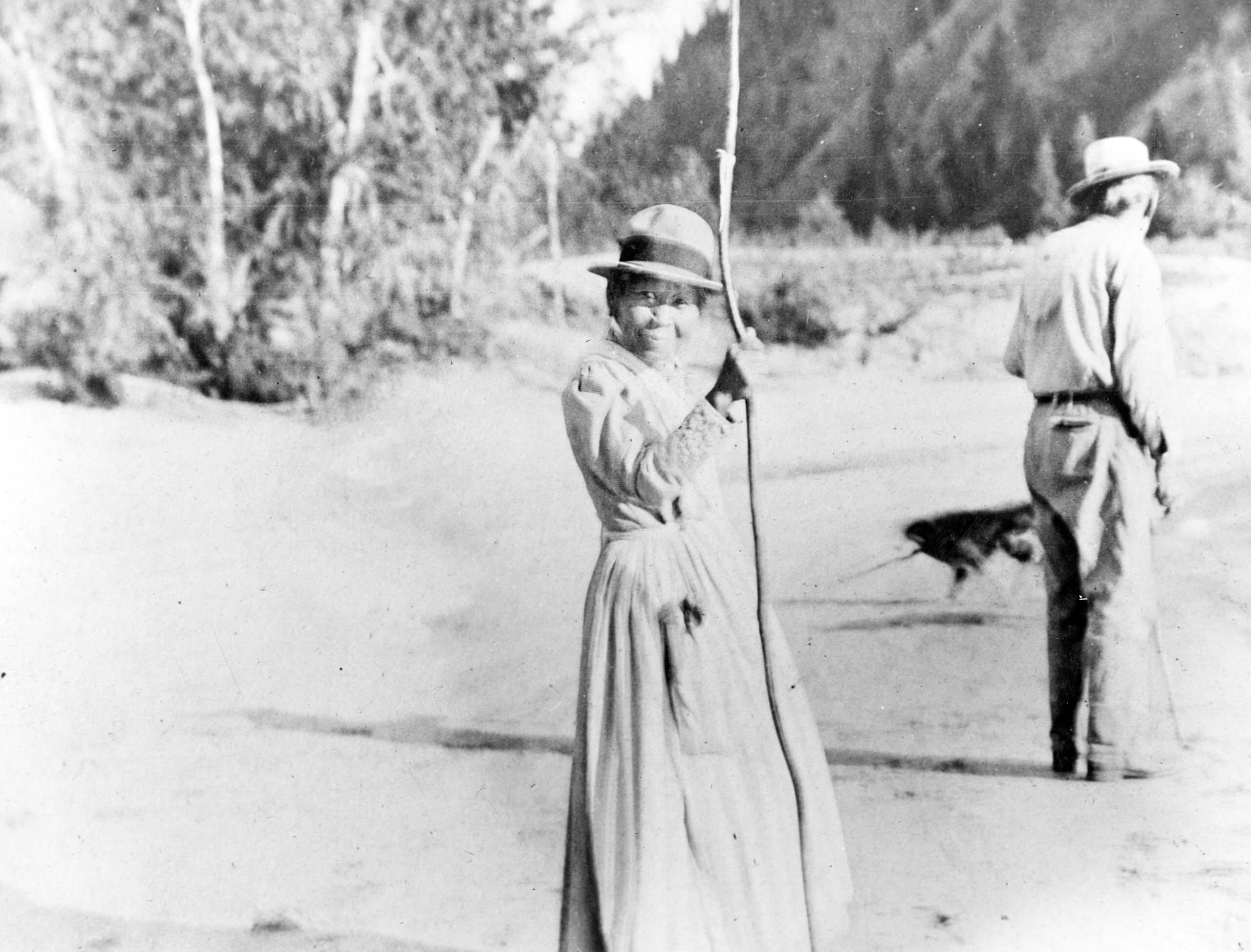 A black-and-white photo of Polly Bemis standing looking at the camera holding a large walking stick.