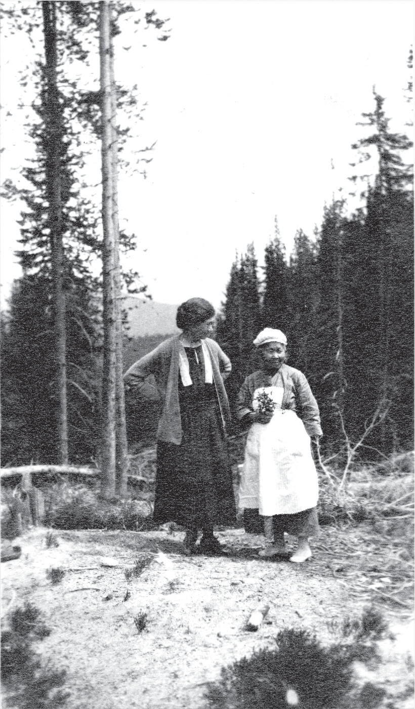 A black-and-white photo of Polly Bemis standing with Nellie Shupp with alpine scenery behind them.