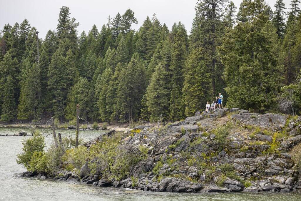 people standing on rocks overlooking Priest Lake with trees in the background