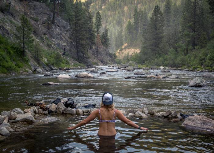 woman stands in natural hot springs along river
