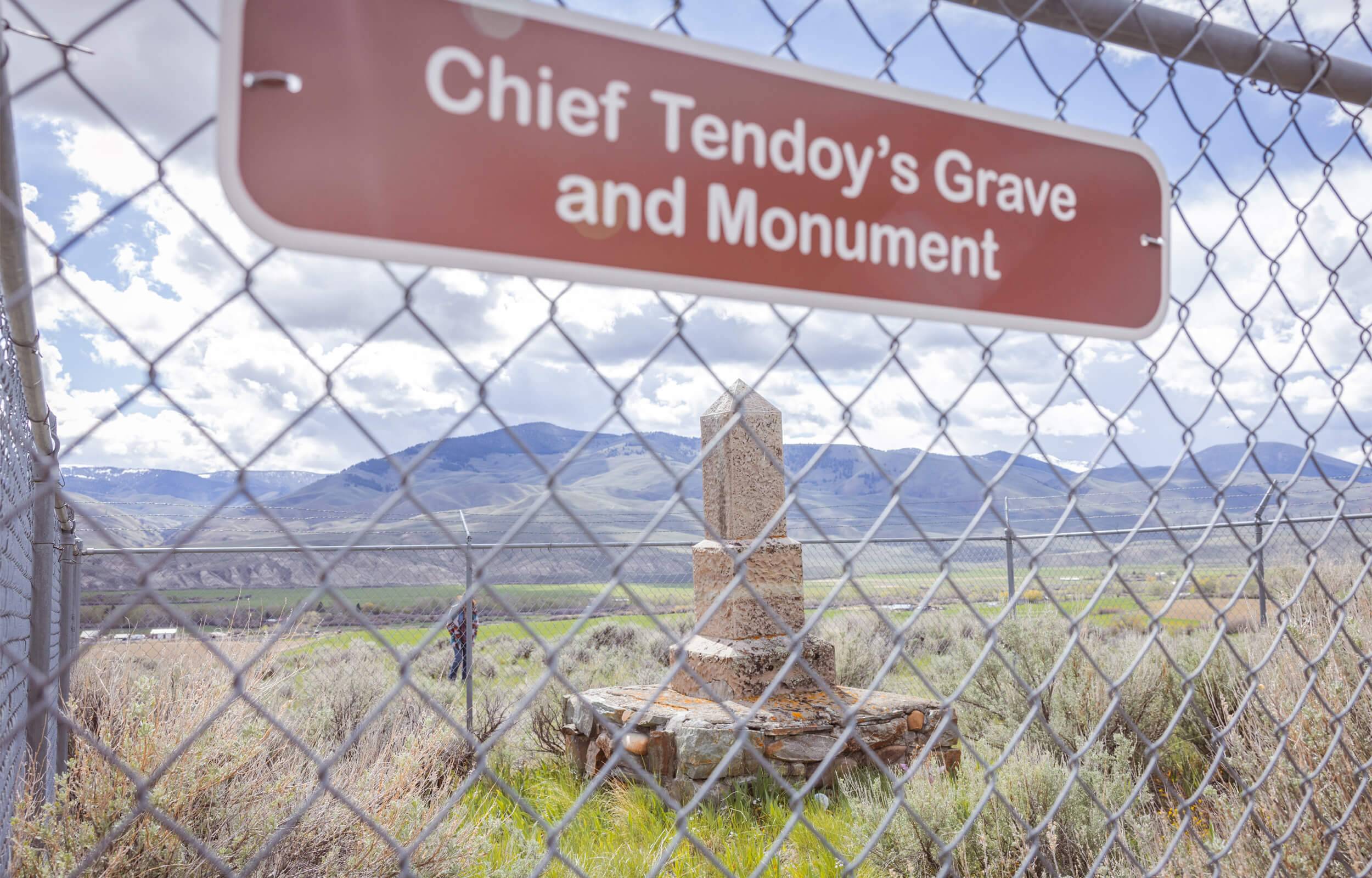 View of the stone Chief Tendoy Grave and Monument from behind a wire fence.