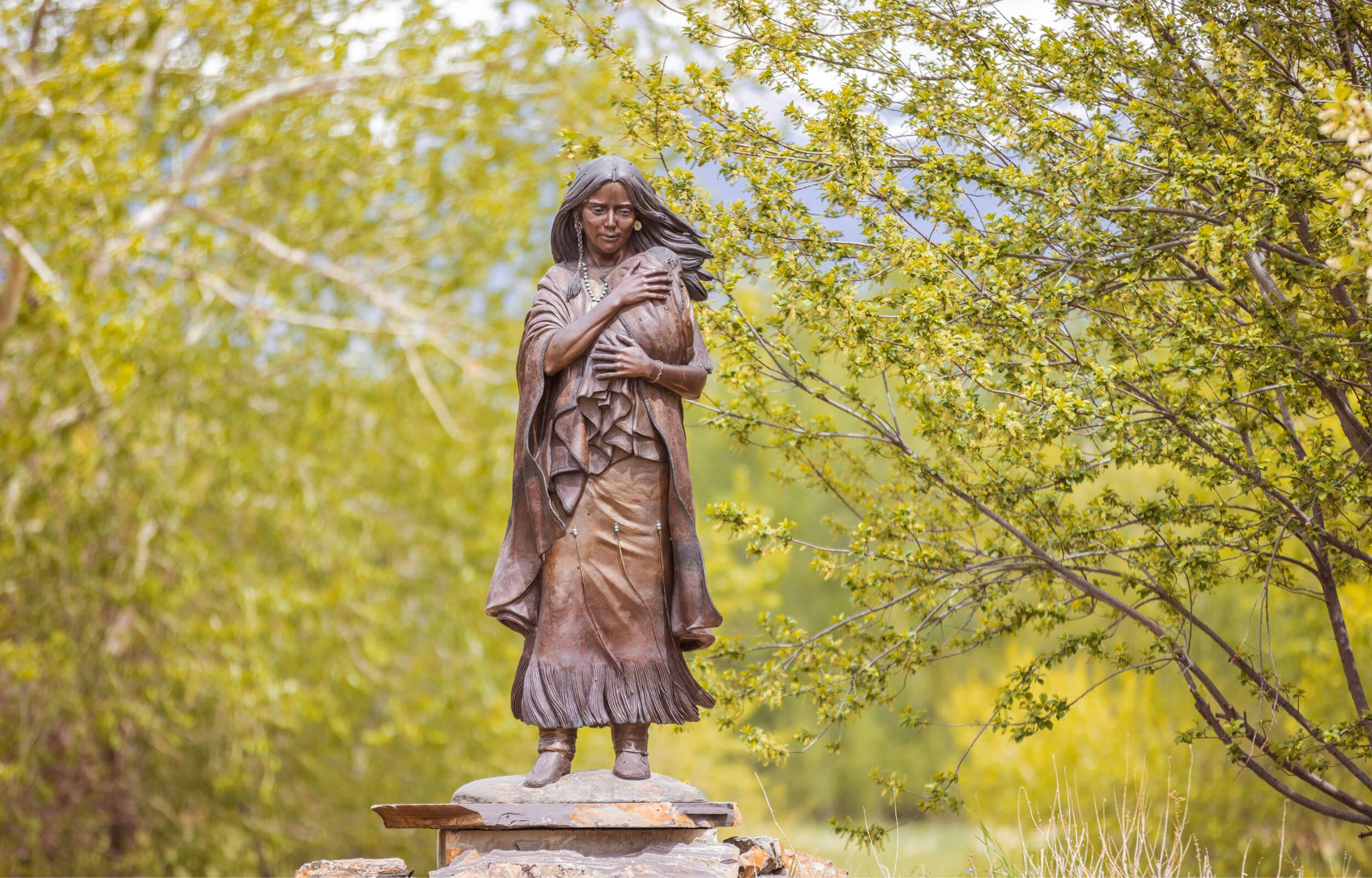 A bronze statue of Sacajawea holding a baby at the Sacajawea Interpretive, Cultural, and Educational Center.