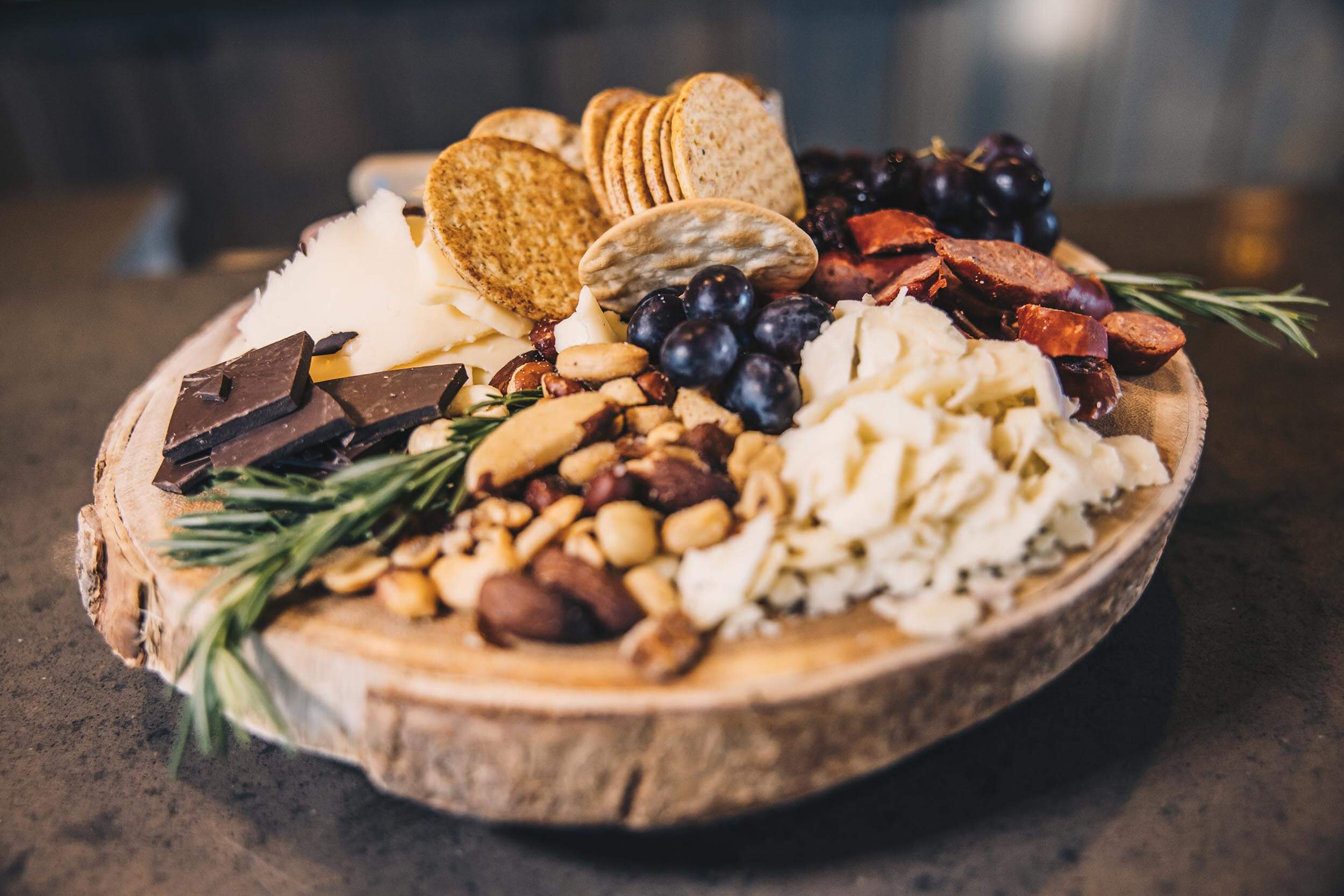 a closeup of a plate of cheese, crackers, grapes, chocolate and nuts