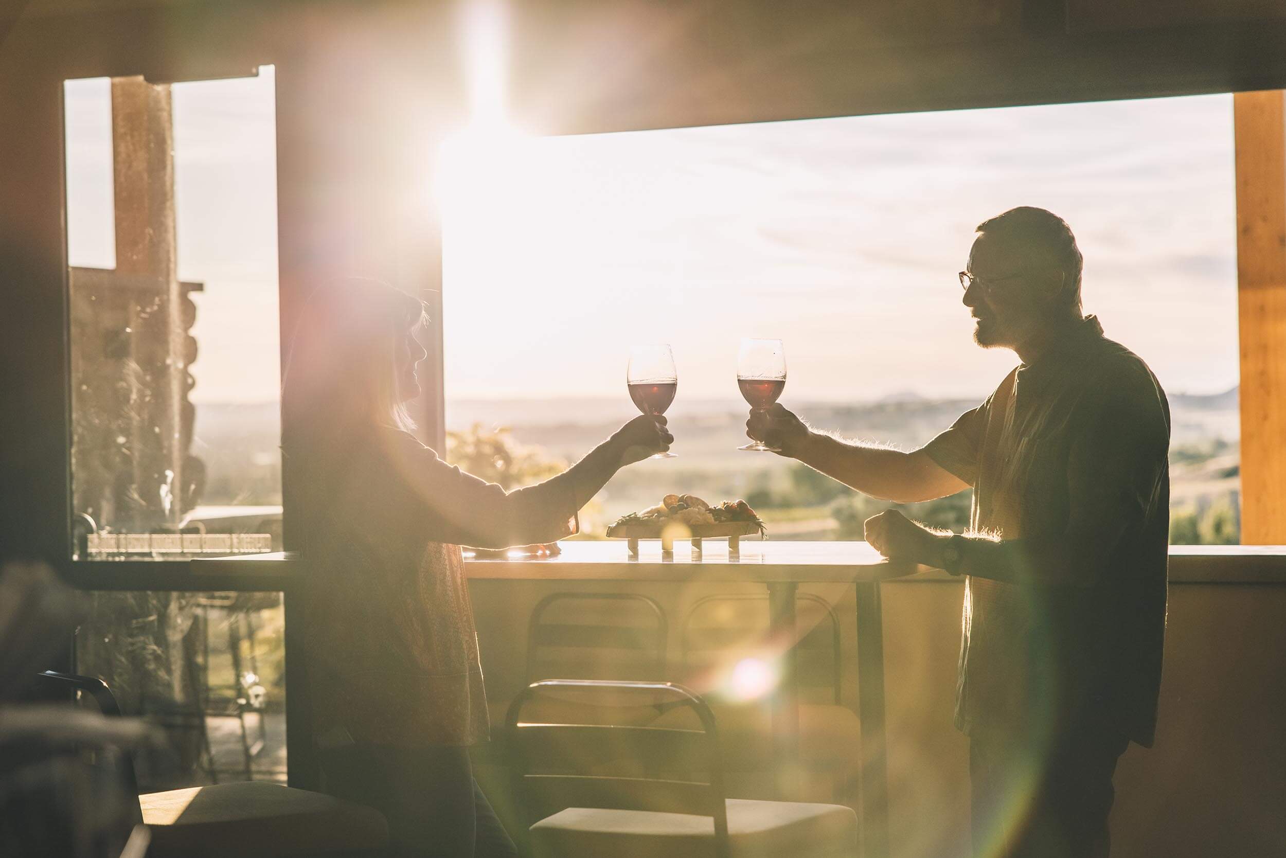 a man and woman holding glasses of wine in an open air room