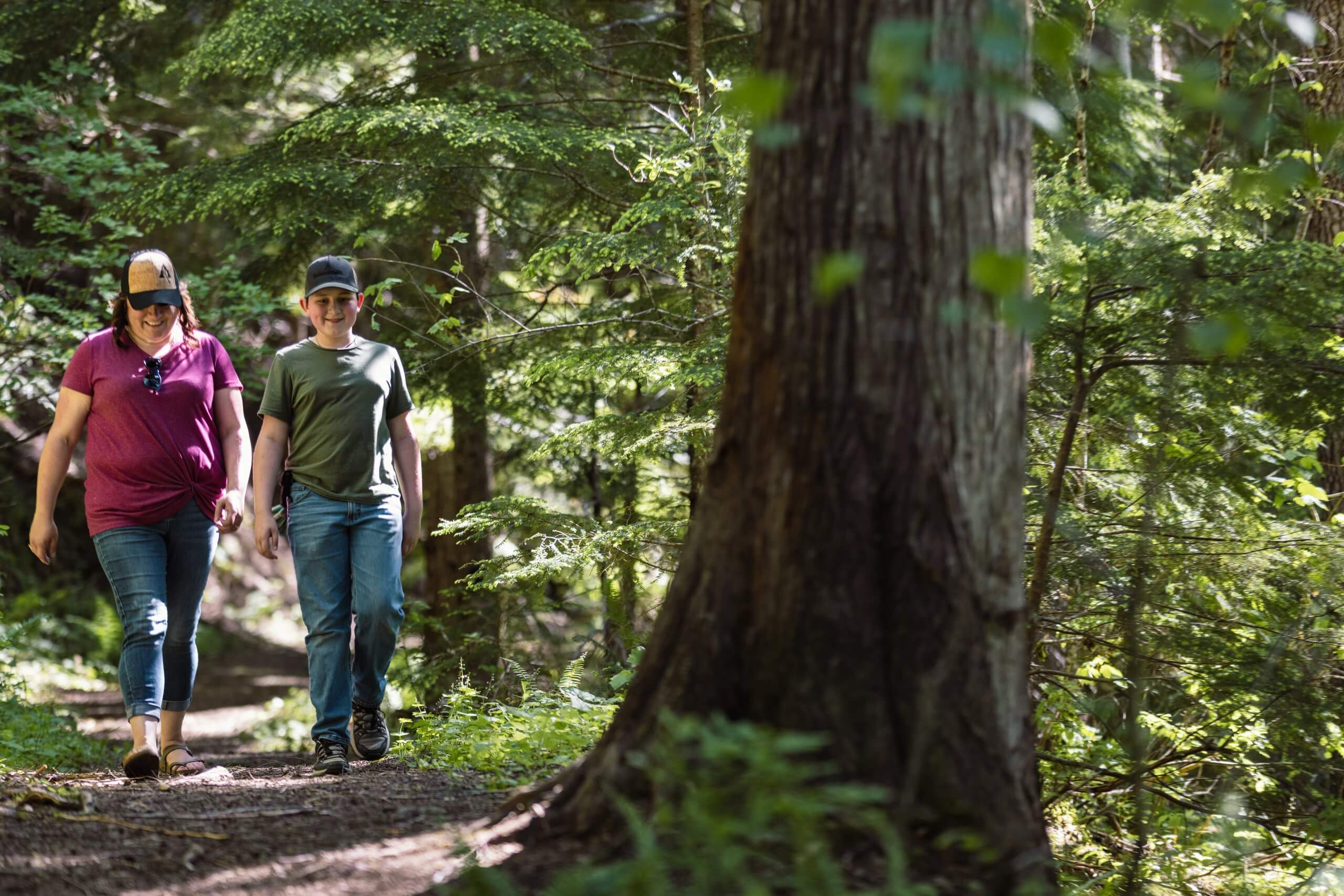 Two people hiking along a forested trail.