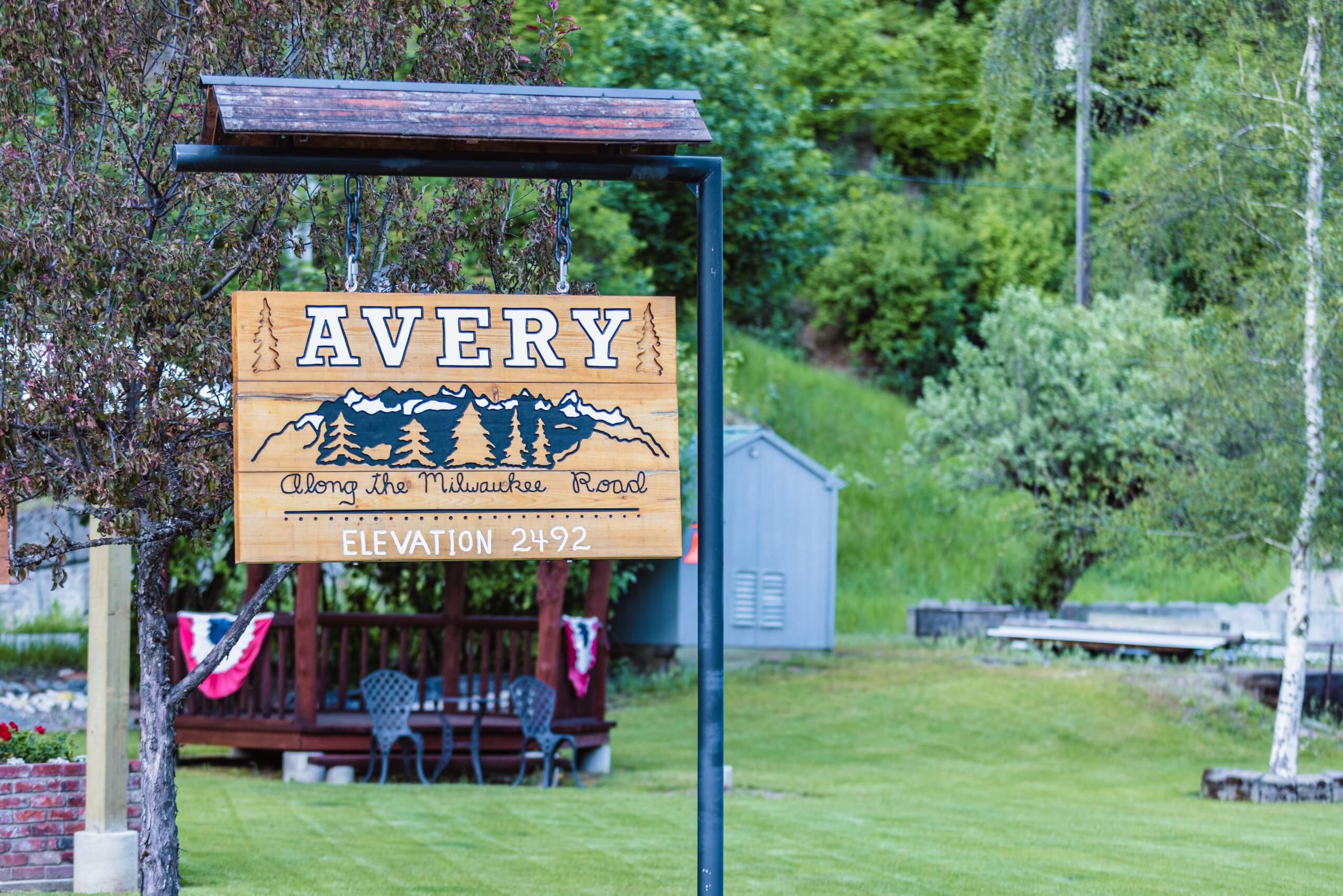 A wooden sign hangs from a post, welcoming visitors to Avery, Idaho.