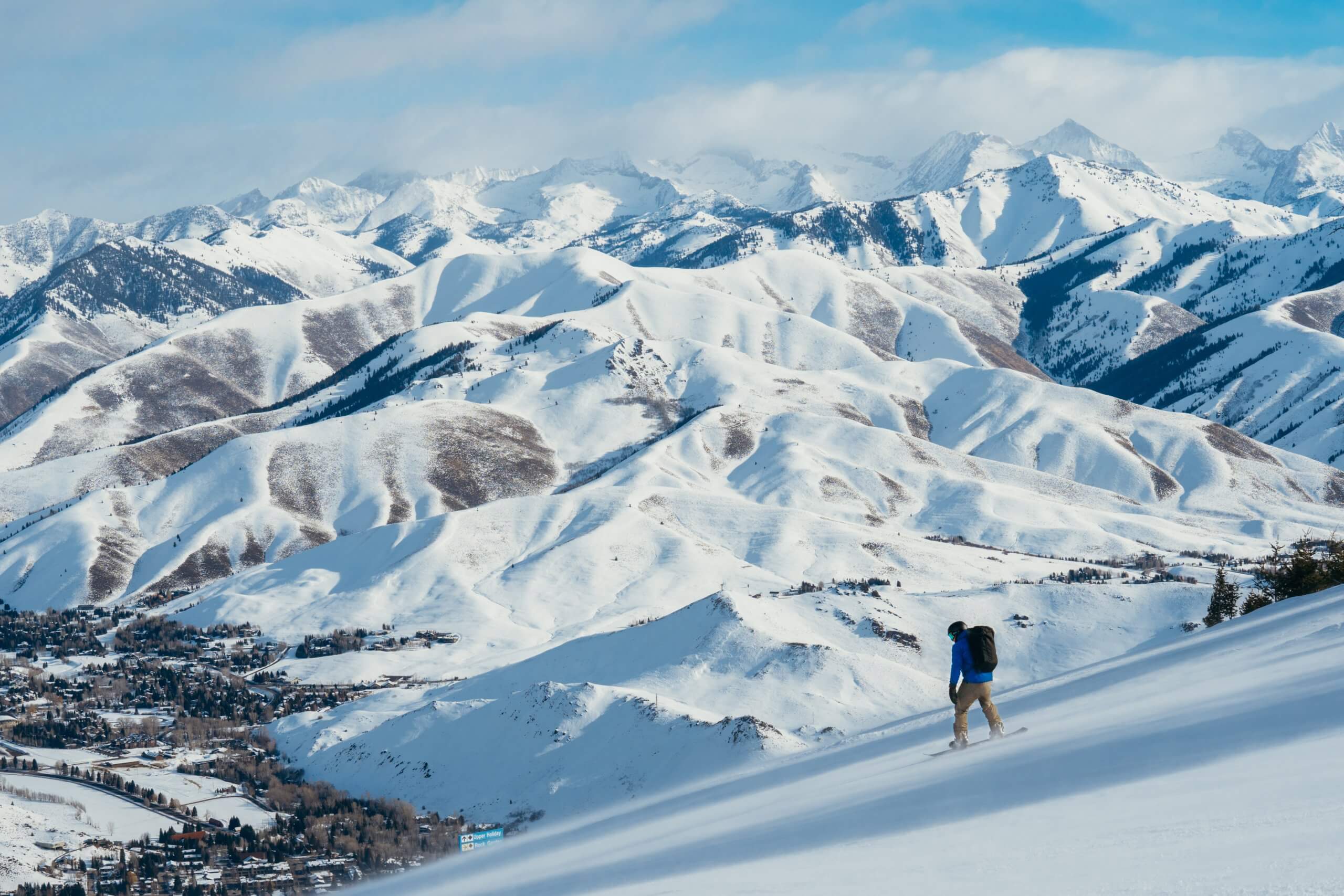 A person snowboarding above Sun Valley with snow-covered mountains in the background.