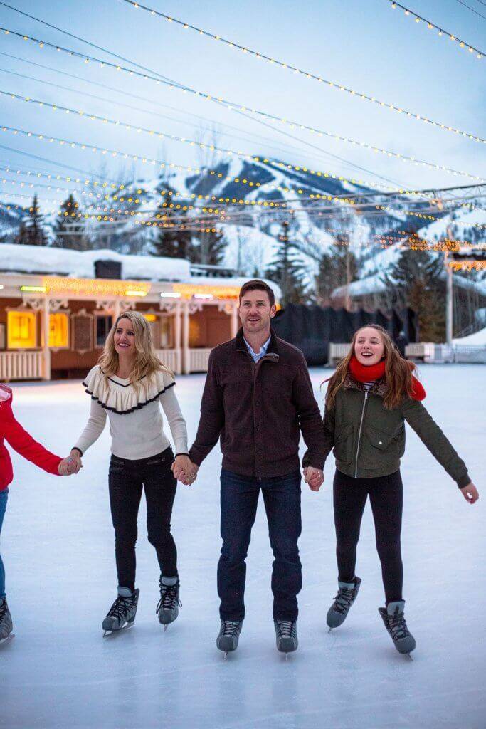 A family holds hands while ice skating at the Sun Valley Ice Rink.