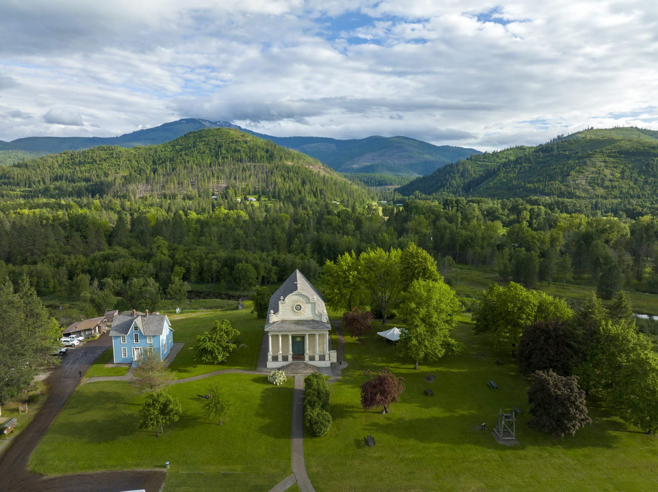 An aerial view of Cataldo Mission, surrounded by grass and trees.
