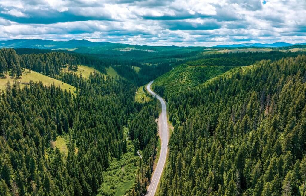 An aerial shot of White Pine Scenic Byway surrounded by green forests and mountains. 